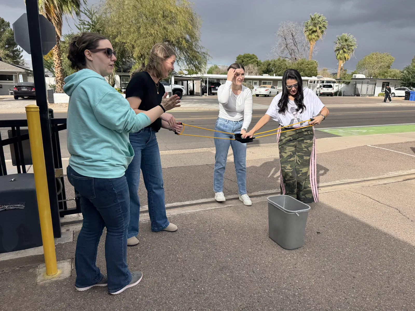 Four colleagues coordinating an outdoor team challenge with shared elastic cords.